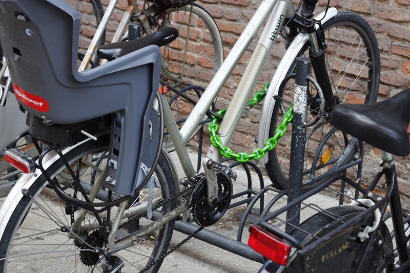 Une chaîne avec cadenas lie la roue avant et le cadre à un point fixe et verrouille aussi un gros câble d'acier qui lie la roue arrière.